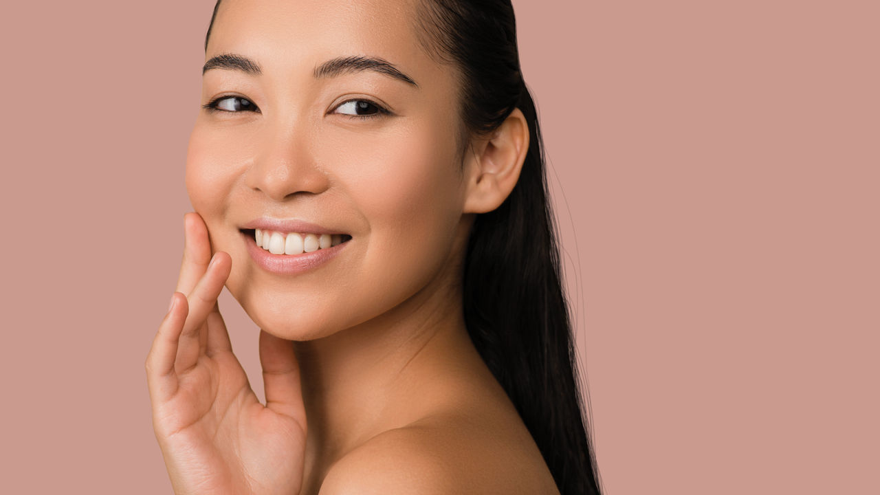 woman looking forward smiling touching her right chin